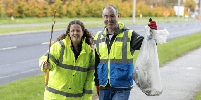  Two employees volunteering by picking up trash.