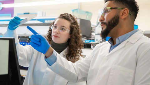 Two Regeneron scientists working together in a lab and examining a container.