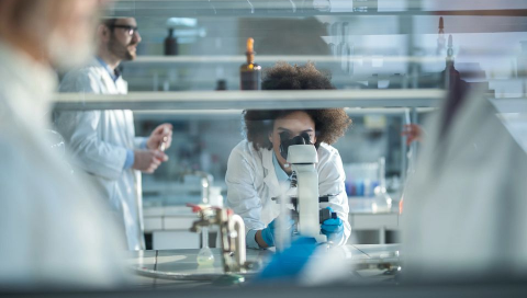 Regeneron scientist looking into a microscope.