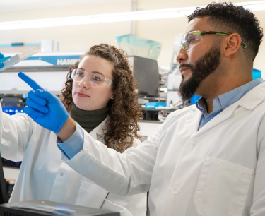 Two Regeneron scientists working together in a lab and examining a container.